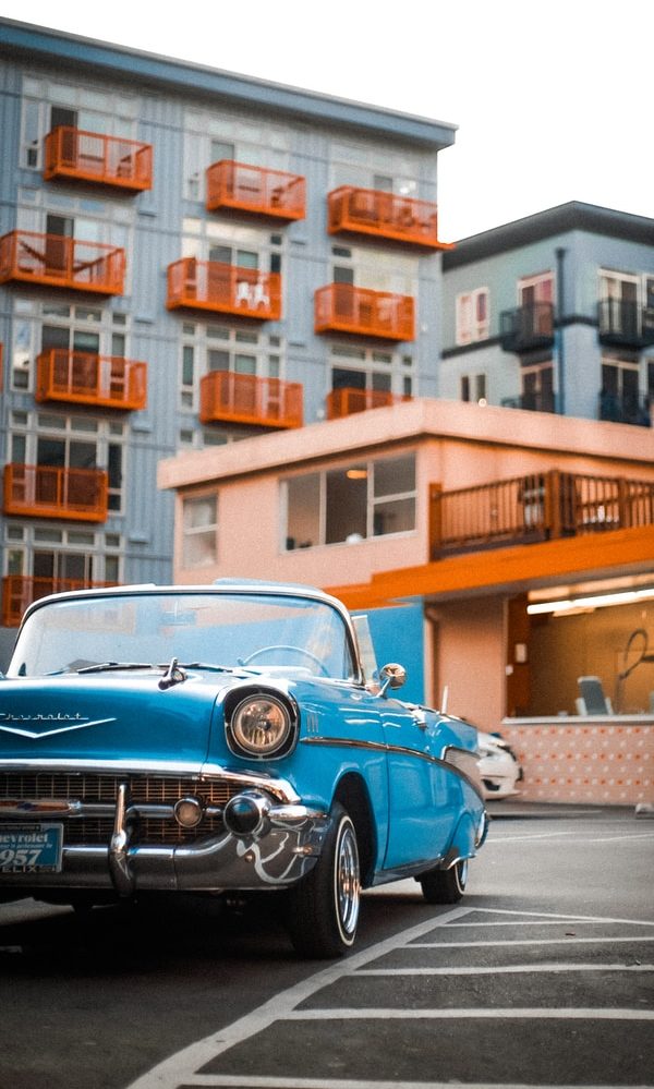 blue car parked near brown building during daytime